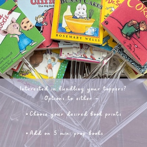 Pu&ograve; includere: Una collezione di mini topper a forma di libro con copertine colorate come Bunny Cakes e Corduroy, fissati su steli in acrilico trasparente ritorti. L'immagine include il testo: Interested in bundling your toppers? Options to either - Choose your desired book prints - Add on 5 mini prop books.
