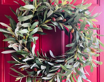 May include: A green olive branch wreath with brown olives, perfect for a front door decoration.