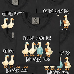 May include: Black t-shirts with the text "GETTING READY FOR LAB WEEK 2026" and a graphic of cartoon ducks wearing lab coats and goggles. The shirts are XL size.