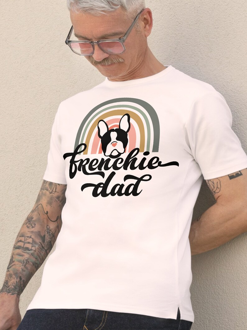 A gay French Bulldog dog dad tshirt - the perfect gift for him! This tee features a Pride rainbow and a French bull dog graphic with the words Frenchie dad in decorative writing. Celebrate the gay man in your life and the bond between him and his dog