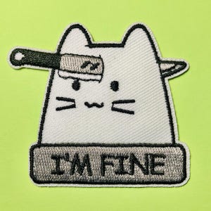 Puede incluir: Un parche bordado blanco que muestra un gato estilizado con un cuchillo atravesando su cabeza. El gato tiene ojos, bigotes y boca negros. Debajo del gato, una franja rectangular gris contiene el texto bordado en negro I'M FINE.