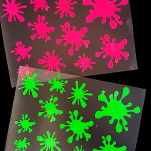 Peut inclure: Deux feuilles de matériau transparent avec des motifs d'éclaboussures rose fluo et vert. Les éclaboussures varient en taille et en forme, créant un motif ludique. Ces motifs sont probablement destinés à l'artisanat ou à la décoration.