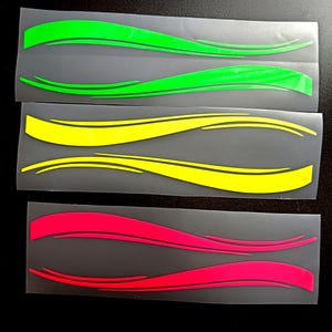 May include: Three sets of vinyl decals in vibrant colors: green, yellow, and red. Each set features two curved, wave-like designs with a black outline. The decals are on a clear backing, ready for application.