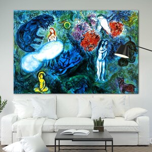 Op de afbeelding: Grote, kleurrijke abstracte kunstafdruk met figuren, dieren en hemelse elementen in tinten blauw, rood en geel. Het kunstwerk wordt tentoongesteld boven een witte bank in een woonkamer.