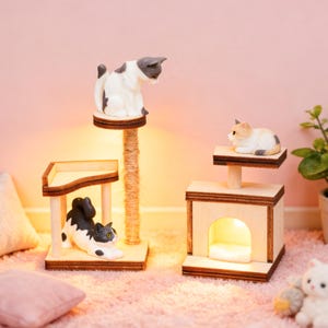 May include: Miniature cat furniture set with three wooden structures. Includes a scratching post, a platform, and a cat house, each with a small cat figurine. The set is made of light-colored wood and rope, with a pink background.