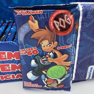 May include: A blue POG card pack with a cartoon boy in a basketball jersey. The pack displays "STACK'EM AND SLAM'EM" and "COLLECT ALL 60". The POG logo is prominent, alongside the text "SERIES 1". The packaging is sealed.