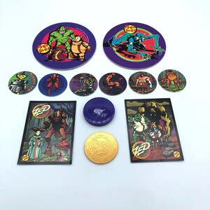 May include: A collection of vintage Planet Zed trading cards, circular game pieces, and a purple container. The cards and game pieces feature colorful illustrations of various alien characters. The gold coin has the text "Snack Shack" on it.