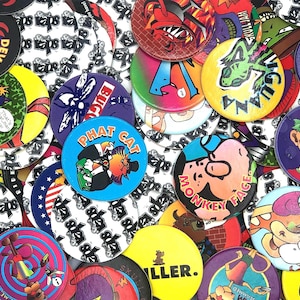 Puede incluir: Una colección de coloridos Pogs, también conocidos como chapas de leche, con varios personajes de dibujos animados y texto. Los Pogs tienen diferentes diseños, incluyendo un diablo, un insecto y las palabras "Phat Cat" y "Monkey Face."