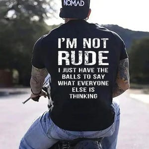 Puede incluir: Camiseta negra con el texto "I'M NOT RUDE" en letras blancas. Debajo, la frase "I JUST HAVE THE BALLS TO SAY WHAT EVERYONE ELSE IS THINKING". Tambi&eacute;n se ve una gorra negra con la palabra "NOMAD".