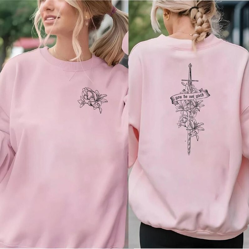 a woman wearing a pink sweatshirt with a cross on it