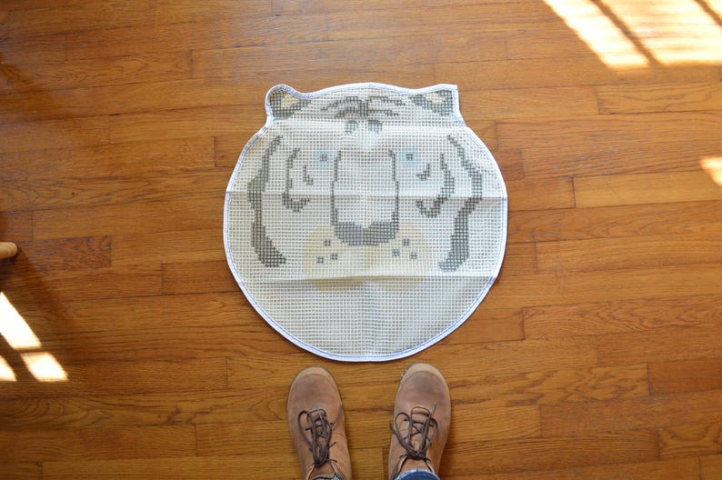 May include: White and grey embroidered tiger rug with a white background and grey tiger face. The rug is circular and has a textured surface.