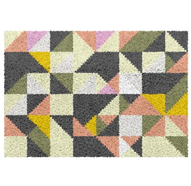 May include: A geometric patterned rug featuring a range of colours, including pink, yellow, green, and grey. The rug is made from a soft, fluffy material.