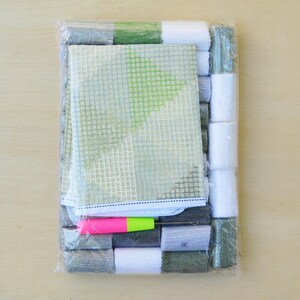 May include: A plastic-wrapped kit for cross-stitch embroidery. It includes a green and white canvas, floss in various colors, a needle, and instructions.