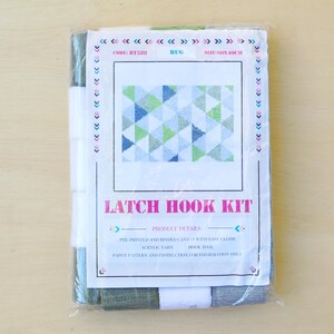 May include: A latch hook kit with a pre-printed canvas, yarn, and latch hook tool. The design features a geometric pattern of blue, green, and white triangles. The kit includes paper patterns and instructions for the project.