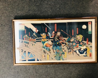 May include: A framed Japanese woodblock print depicting a nighttime scene of samurai warriors fighting on a bridge. The print is in vibrant colors, including red, blue, green, and yellow. The warriors are depicted in dynamic poses, with swords drawn and expressions of determination on their faces. The bridge is made of wood and has a curved design. The background is a dark blue sky with a full moon.