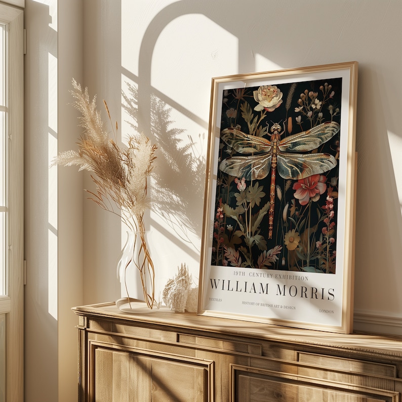 May include: A framed poster with a vintage aesthetic featuring a dragonfly with intricate details, surrounded by floral elements. The poster is titled "19th Century Exhibition William Morris" with the text "Textiles, History of British Art & Design, London".