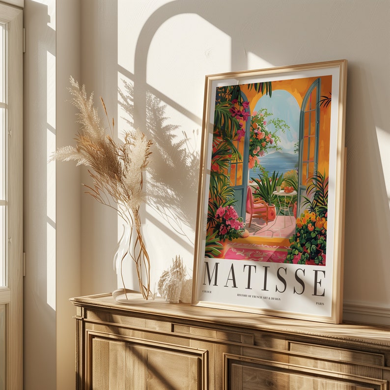 May include: A framed print of a painting by Henri Matisse, depicting a colorful garden scene with a view of the sea through an open doorway. The print is titled "Matisse" and features the text "History of French Art & Design" and "Paris".