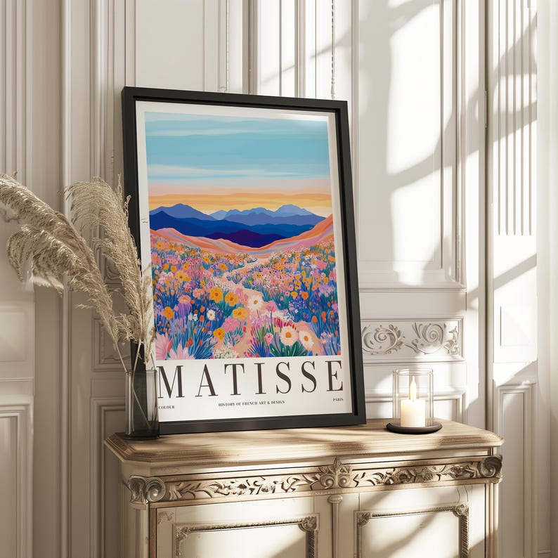 May include: A framed poster with a colorful illustration of a mountain landscape with a path leading through a field of flowers. The text "MATISSE" is printed at the bottom of the poster.