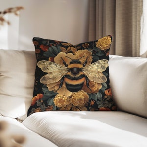 Puede incluir: Una almohada con un fondo negro que presenta una abeja grande rodeada de flores amarillas y naranjas. La abeja tiene rayas negras y amarillas y est&aacute; enfocada.