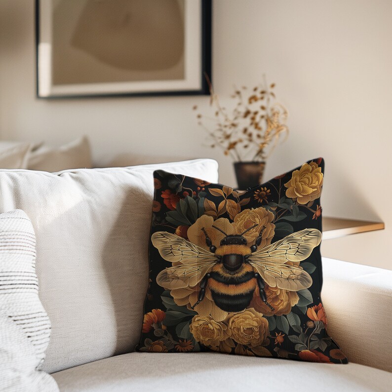 Puede incluir: Una almohada negra con un patr&oacute;n floral que presenta un gran abejorro en el centro. Las flores son amarillas y naranjas con hojas verdes. El fondo es negro.