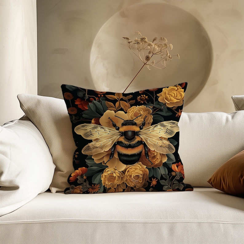 Puede incluir: Una almohada negra con un patr&oacute;n floral que presenta un gran abejorro en el centro. Las flores son amarillas, naranjas y rojas. El fondo es negro.