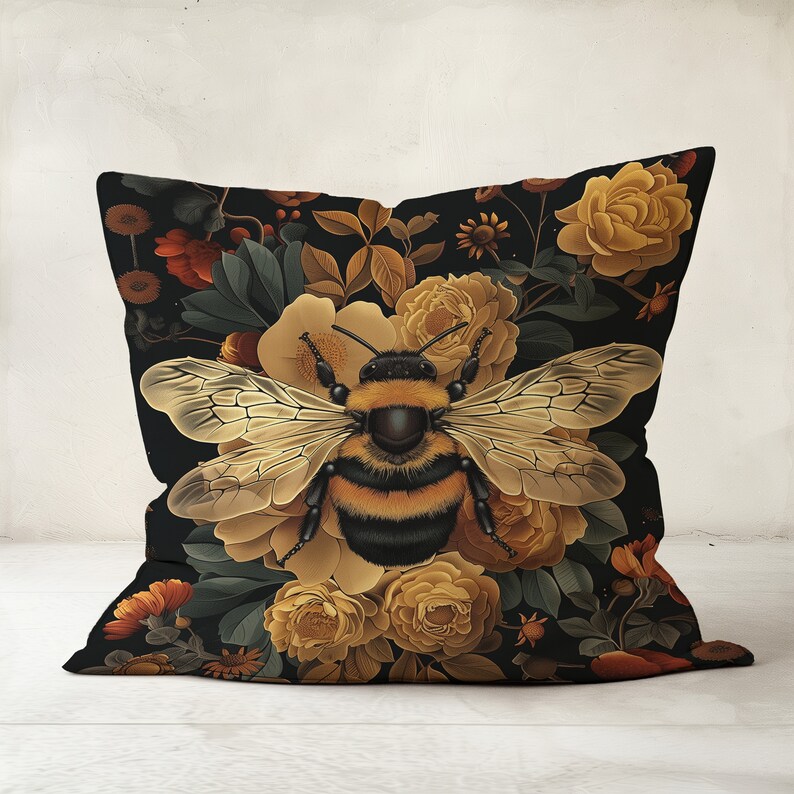 Puede incluir: Una almohada negra con un patr&oacute;n floral que presenta un gran abejorro en el centro. Las flores son amarillas, naranjas y marrones.