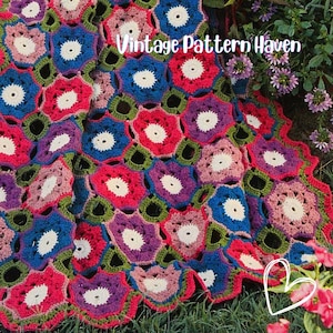 May include: A colorful, handmade crochet blanket featuring a floral pattern. The blanket showcases a variety of colors, including red, blue, purple, and green. The text "Vintage Pattern Haven" is visible on the blanket.