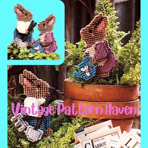 以下が含まれることがあります： ヴィンテージのプラスチックキャンバスのパターン。3匹の茶色と白のウサギがガーデニングツールを持っています。ウサギは青、紫、白の服を着ています。パターンは「ヴィンテージパターンヘブン」というタイトルです。