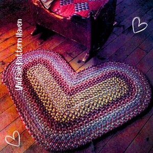 May include: A heart-shaped braided rug with a mix of red, yellow, and blue hues. The rug is on a wooden floor, with a rocking chair in the background. The text "Vintage Pattern Haven" is on the left side of the rug.