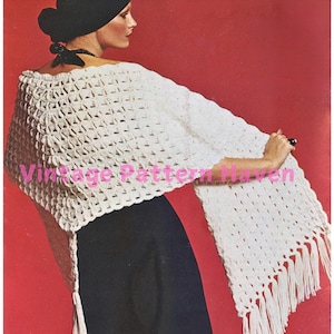 Può includere: Poncho in crochet bianco con frange. Il poncho è realizzato con un punto a pizzo e ha un'ampia scollatura.