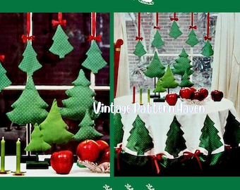 May include: A festive Christmas display featuring green fabric Christmas trees with red bows and apples. Some trees are hanging, others are on a table with a white tablecloth. The text "Vintage Pattern Haven" is visible.