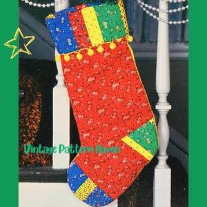 May include: A quilted Christmas stocking with a red floral pattern, accented with blue, green, and yellow panels. The top edge features a row of yellow pom-poms. The text "Vintage Pattern Haven" is visible on the stocking.