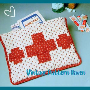 Puede incluir: Un botiquín acolchado con un diseño de cruz roja. El kit es blanco con un pequeño estampado floral y un borde rojo. Contiene tiritas, crema y pastillas. El texto "Vintage Pattern Haven" es visible.