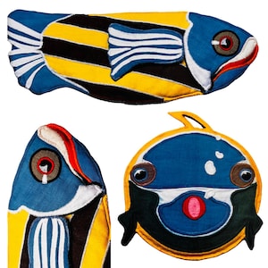 May include: Three colorful felt fish toys. One fish is yellow and black with blue stripes and a blue head. Another fish is blue with black eyes and a pink mouth. The third fish is blue with black stripes and a yellow tail.