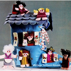 May include: A blue felt boot with a white lace-up closure and red polka dots. The boot is decorated with felt figures of people, including a girl with yellow hair on the roof, a girl with red hair looking out the window, and a girl with brown hair standing in the doorway. The boot is a playhouse for the felt figures.