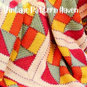 Peut inclure: Une couverture au crochet avec un motif de patchwork dans des tons de rouge, orange, jaune et vert. La couverture a une bordure blanche avec un point texturé.