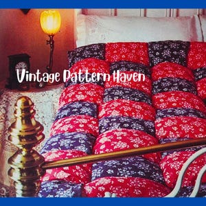 May include: A vintage quilt with a floral pattern in red and navy blue, arranged in a grid pattern. The quilt is on a bed with a white headboard. The text "Vintage Pattern Haven" is overlaid on the image.