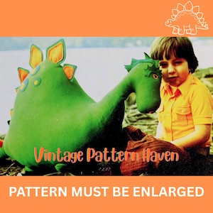 May include: A green dinosaur plush toy with orange and yellow accents, next to a person wearing a yellow shirt. The image has the text "Vintage Pattern Haven" and "PATTERN MUST BE ENLARGED".