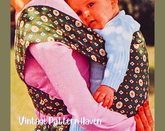 May include: A vintage image of a baby carrier. The carrier is made of a dark green fabric with a floral pattern and is wrapped around a person wearing a pink top. A baby in a light blue sweater is held in the carrier. The text "Vintage Pattern Haven" is visible.