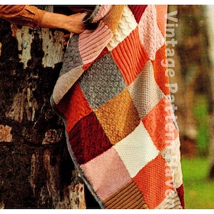 May include: A knitted patchwork blanket with squares in various colours, including pink, orange, brown, and white. The blanket is made with different stitch patterns, creating a textured look.