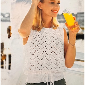 May include: White crochet sleeveless top with a delicate openwork pattern and a drawstring waist.