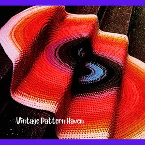 May include: A colorful, crocheted blanket with a wave-like design. The blanket features a gradient of colors, including red, orange, pink, and blue. The text "Vintage Pattern Haven" is visible in the lower left corner. The blanket is made of yarn.