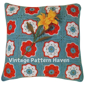 May include: A crocheted pillow with a blue background and red, white, and blue flower designs. A yellow lily is placed on top of the pillow. The text "Vintage Pattern Haven" is printed on the pillow.