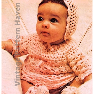 May include: A pink crocheted baby outfit with a matching bonnet and booties. The outfit features a delicate lace pattern and is perfect for a newborn.