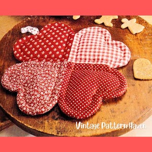 May include: A red and white heart-shaped oven mitt with four sections, each featuring a different pattern: small white dots, tiny white flowers, and a red and white gingham check. The mitt is on a wooden surface with gingerbread cookies and the text "Vintage Pattern Haven".