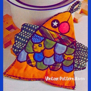 May include: A fabric potholder shaped like a fish, featuring a patchwork design of various colorful patterns including floral, plaid, and polka dots in shades of orange, blue, green, and yellow. It has a hanging loop and the text Vintage Pattern Haven.