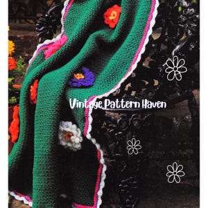 May include: A green crocheted blanket with colorful floral accents. The blanket features red, orange, purple, and white flowers. The border is white with a pink and purple trim. The text "Vintage Pattern Haven" is visible.