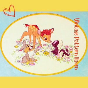 May include: Cross-stitch image of Bambi, Thumper, and Flower in a field of flowers. The characters are rendered in a pixelated style with shades of brown, orange, and black. The artwork is framed with an oval border and the text "Vintage Pattern Haven".