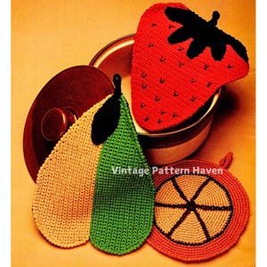 May include: Three crocheted pot holders shaped like a strawberry, pear, and orange. The strawberry is red with a black stem and leaves. The pear is yellow and green with a black stem and leaf. The orange is red with a brown centre and black lines.