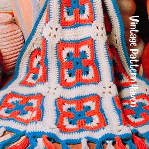 May include: A crocheted blanket with a repeating square pattern in white, red, and blue. The blanket has a blue border and tassels. The text "Vintage Pattern Haven" is visible on the right side of the blanket.